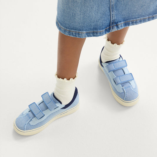 hover | A child modeling The Kids Strap Sneaker in Berry Blue.