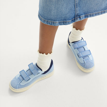 hover | A child modeling The Kids Strap Sneaker in Berry Blue.