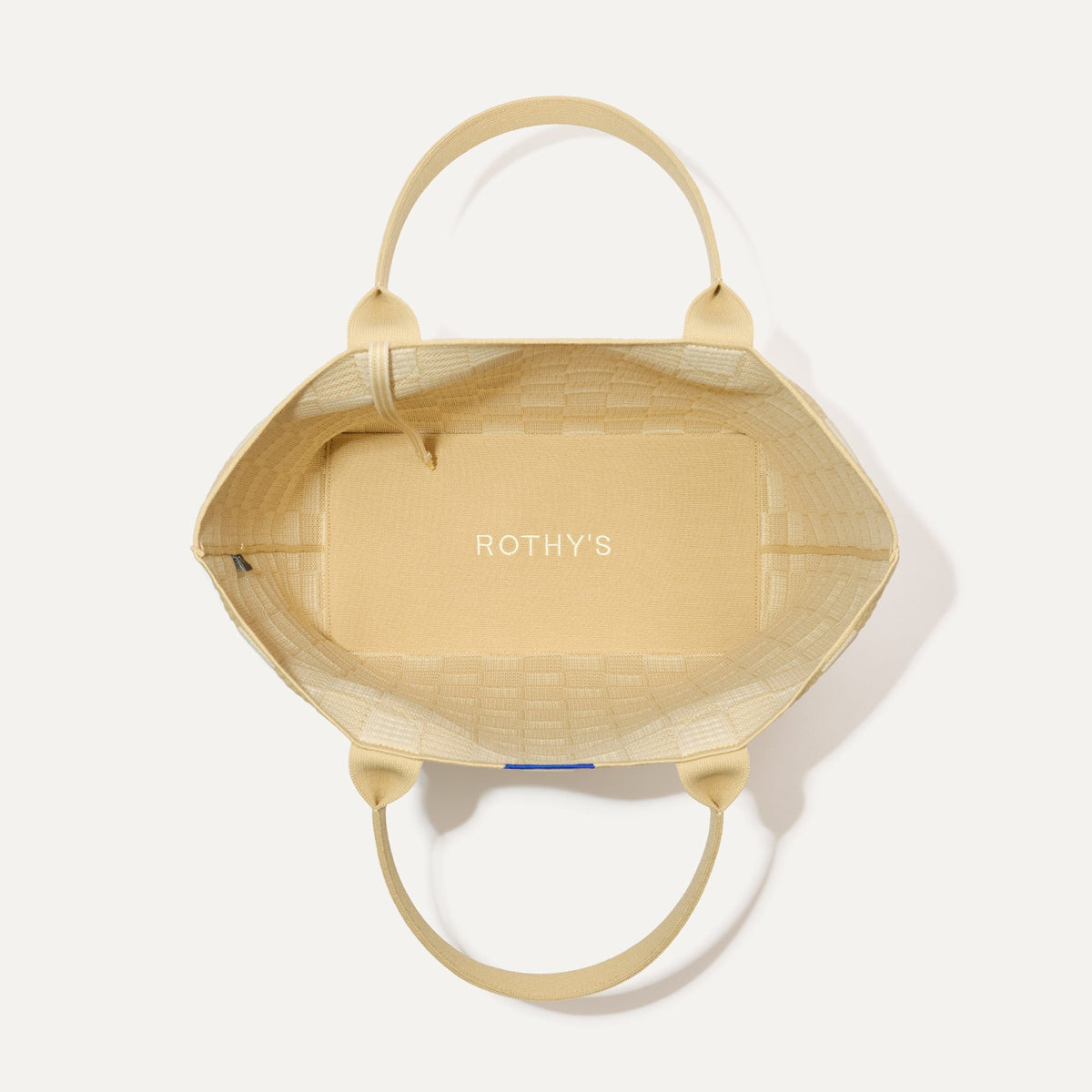 The Lightweight Tote in Checker Sand shown open from the top, with interior visible.