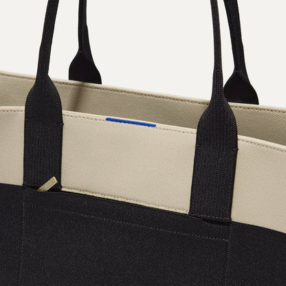 A closeup of The Classic Tote in Luna, focusing on the exterior zip pocket.