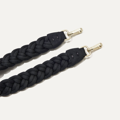 A close-up of The Braided Shoulder Strap in Black, focusing on the end snap hooks.