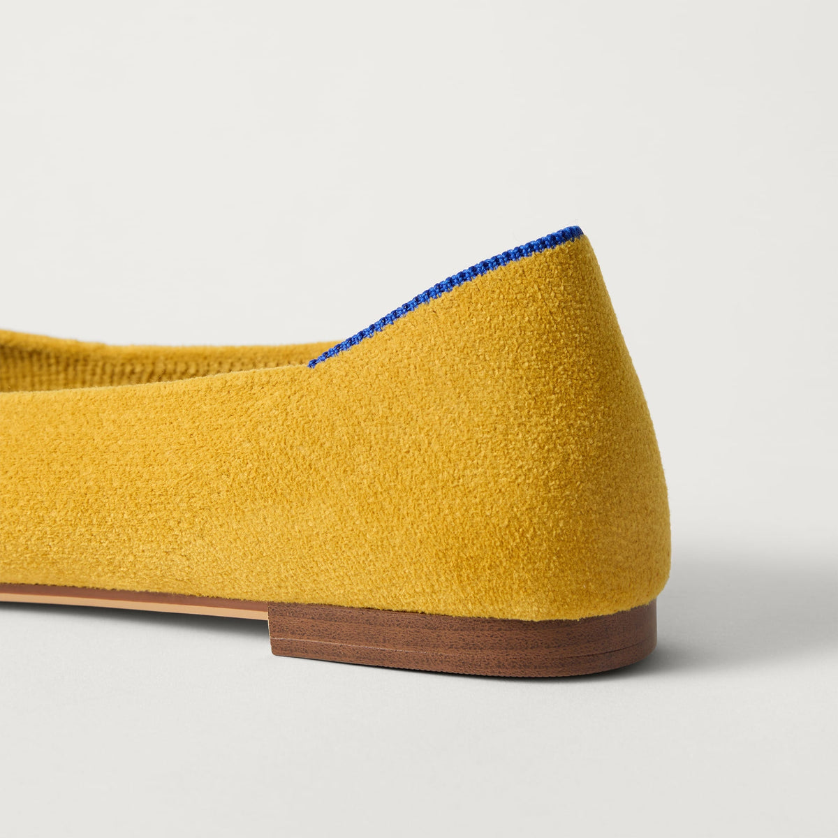 Close up of the heel of The Point III in ReVelvet Saffron, with Rothy's signature blue halo.