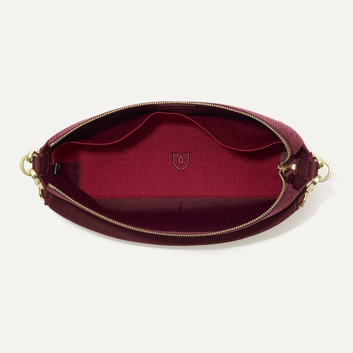 The Daily Crossbody in ReVelvet™ Syrah, shown from the top down, with zipper open and interior exposed.