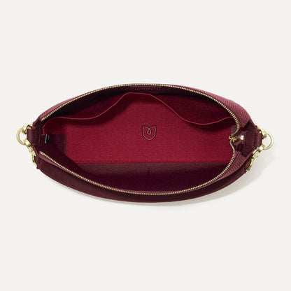 The Daily Crossbody in ReVelvet™ Syrah, shown from the top down, with zipper open and interior exposed.