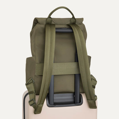 The Travel Cinch Backpack in Forest shown from the back, shown attached to a rolling suitcase using the wrap-around band.
