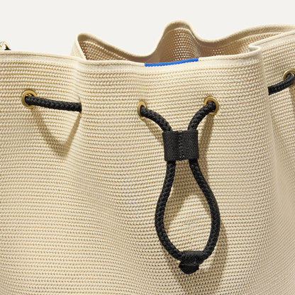 A close up of The Cinch Bucket Bag in Black and White Raffia-Knit showing the drawstring closure.