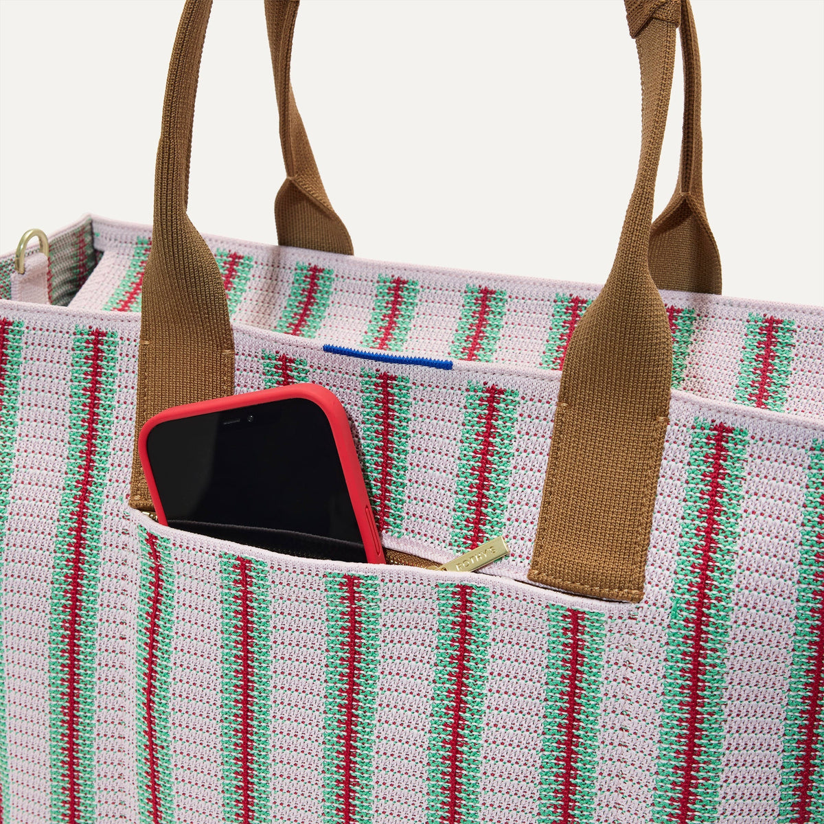 A closeup of The Classic Tote in Watermelon Market Stripe, focusing on the exterior zip pocket.