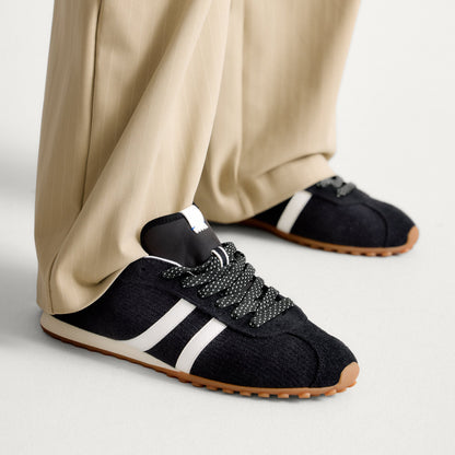 hover | Model wearing The Ivy Sneaker in ReVelvet Black.
