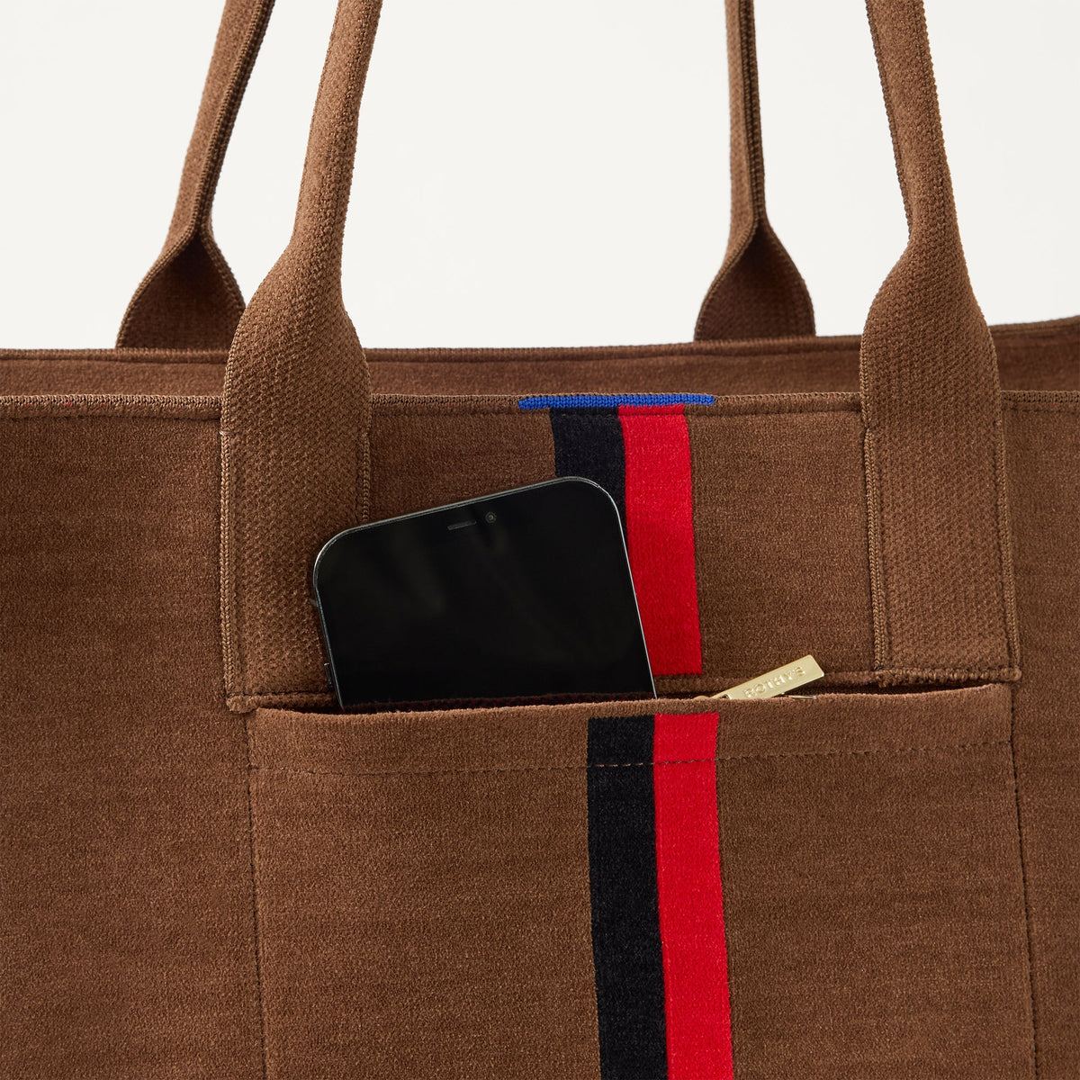 A closeup of The Classic Tote in ReVelvet Cinnamon Stripe, focusing on the exterior zip pocket.