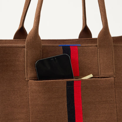 A closeup of The Classic Tote in ReVelvet Cinnamon Stripe, focusing on the exterior zip pocket.
