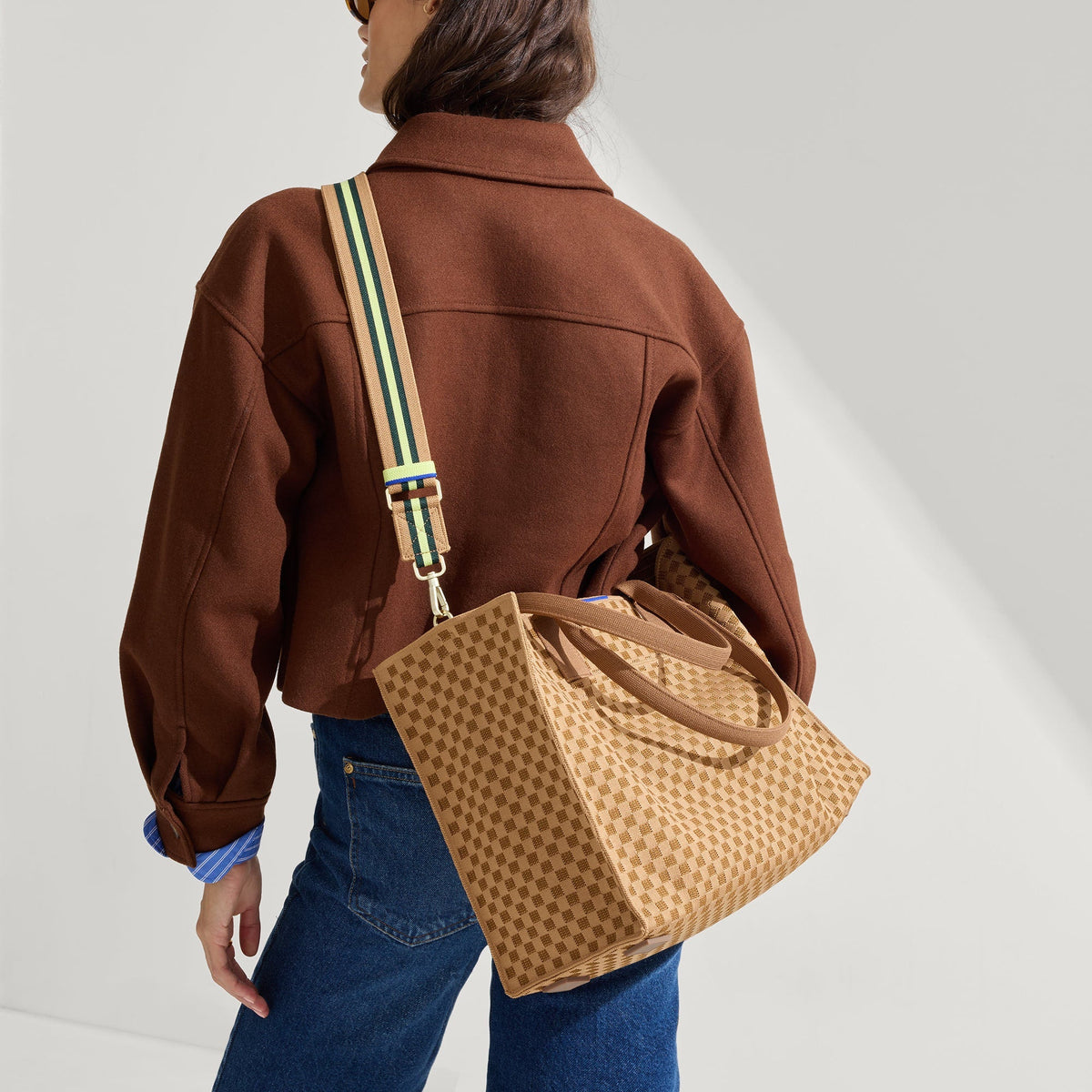 Overlay:: Shown with The Crossbody Strap (sold separately.) | Alt:: The Classic Tote in Hazelnut, worn as a crossbody by a model, paired with The Crossbody Strap in Neon Pine Stripe.
